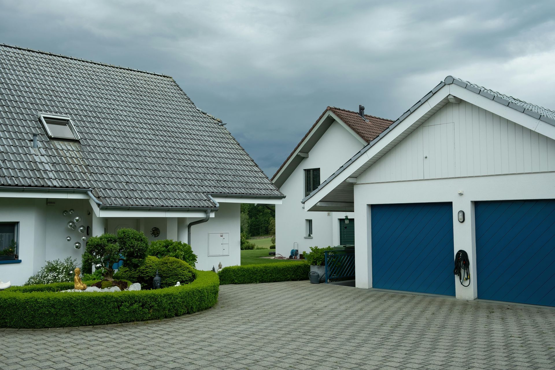 A white house with blue garage doors and a gray roof