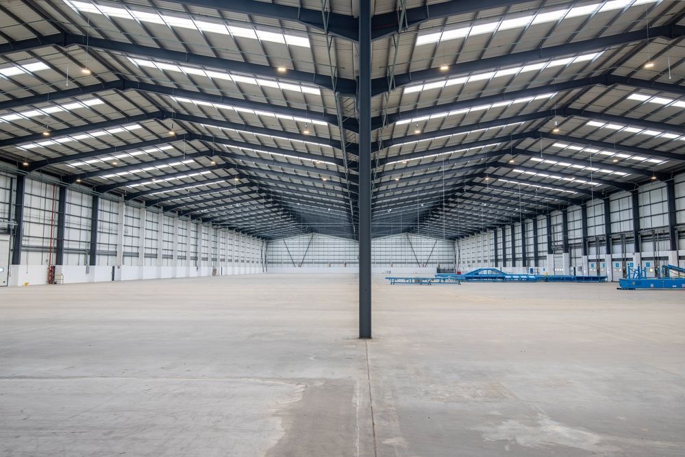 A large empty warehouse with a lot of windows and a concrete floor.