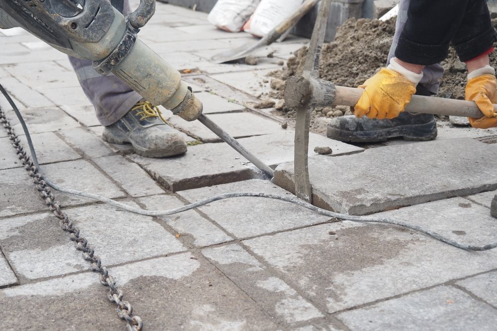 A construction worker is using a hammer to drill a hole in the ground.