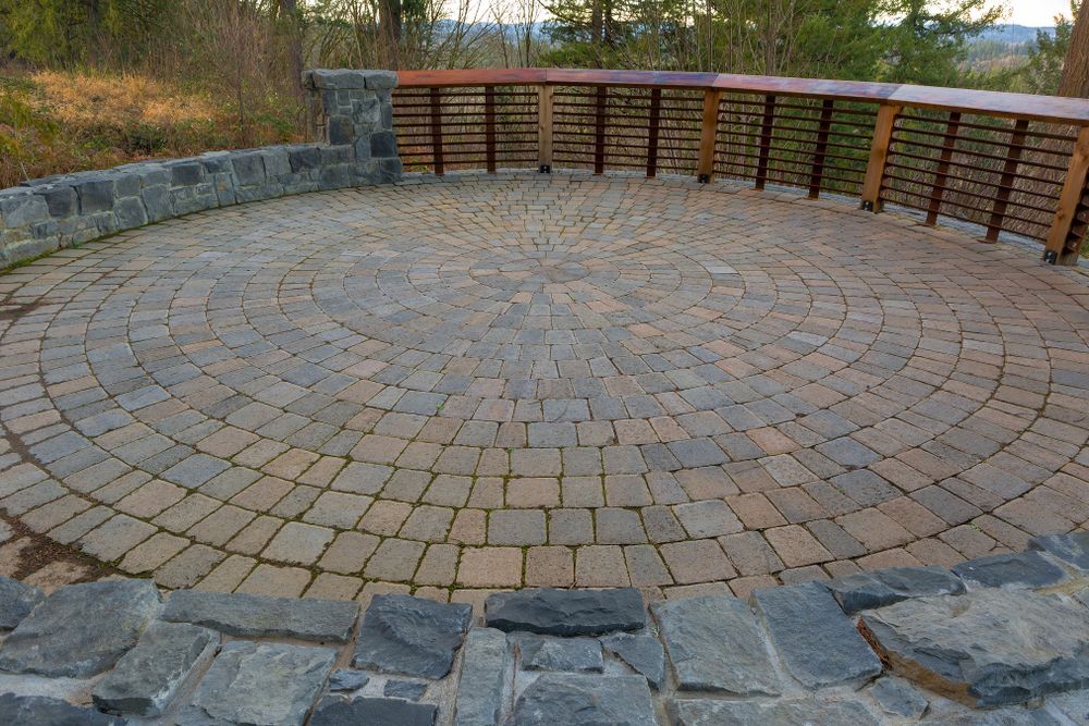 A circular brick patio with a wooden bench in the middle
