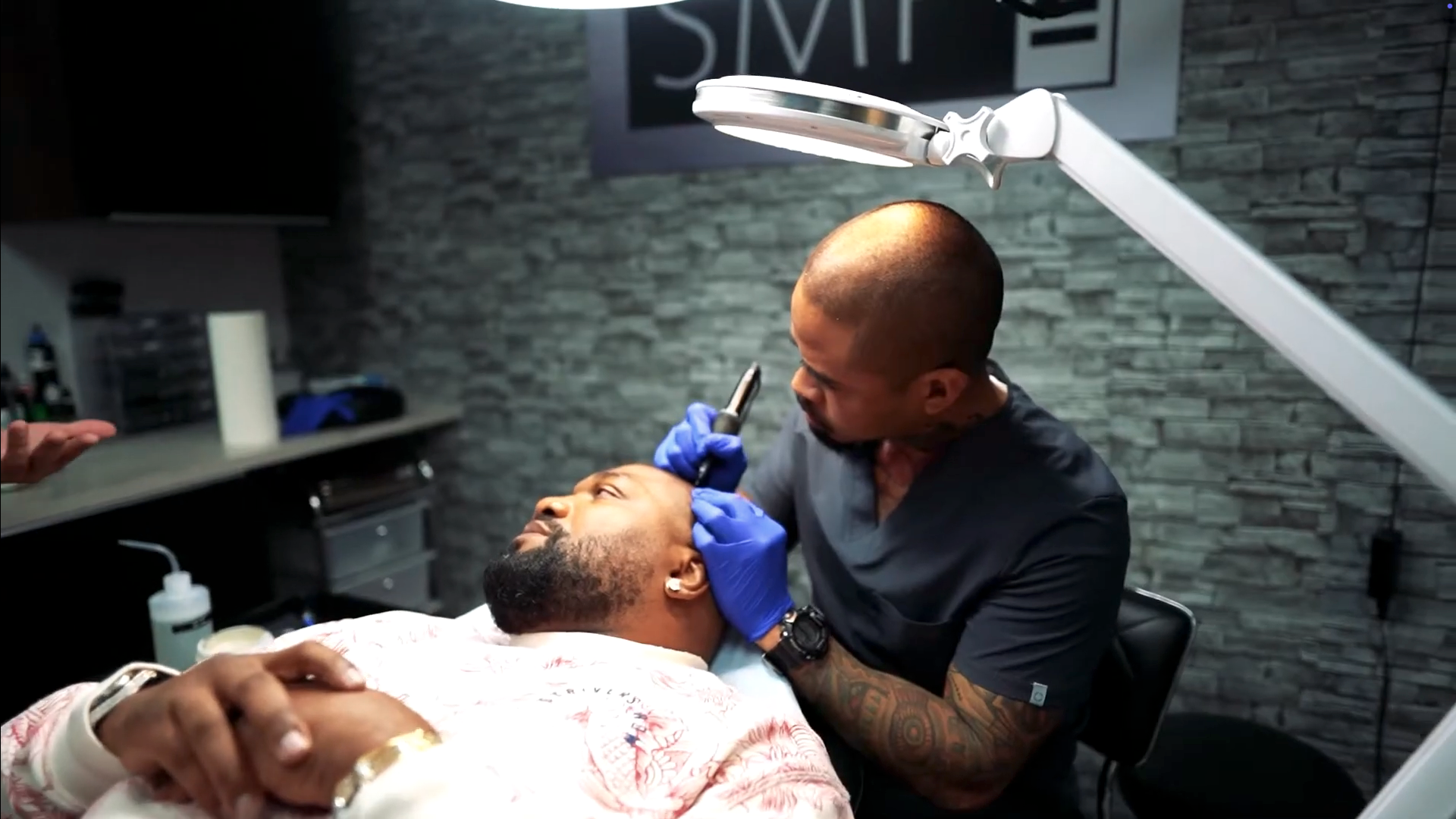 An SMP INK CDA Student Practitioner drawing the reference line on the scalp of  an SMP client in a class setting.