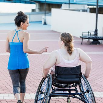 NDIS community access. Two women go for a run in the city - one on foot and the other in a wheelchair.