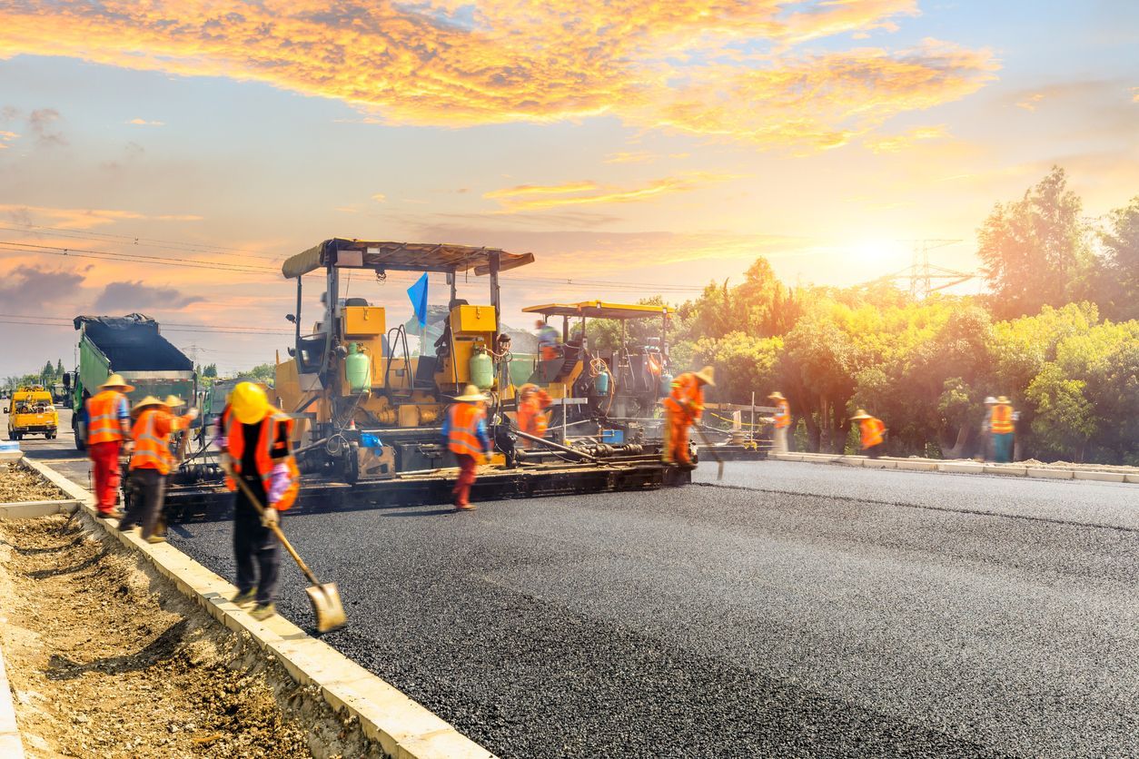 Un grupo de trabajadores de la construcción está colocando asfalto en una autopista.