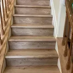 Wooden staircase with light brown treads and railing.