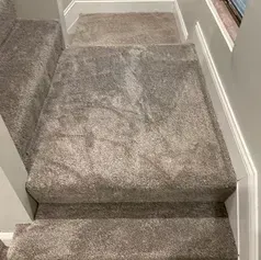 Carpeted staircase with gray carpeting and white trim.
