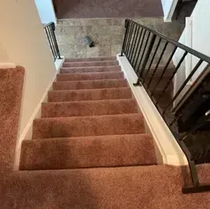 Staircase with brown carpet and black railing. Top-down view.