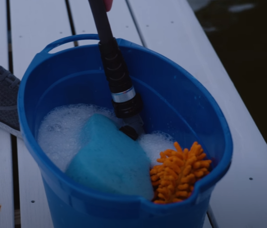 Blue bucket with boat cleaning supplies, such as a sponge, soup, towel.