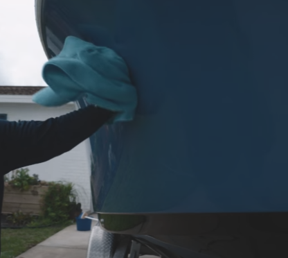 Drying dark blue boat with light blue chamois towel