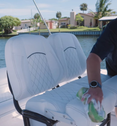 Man detailing white vinyl chairs on a boat.