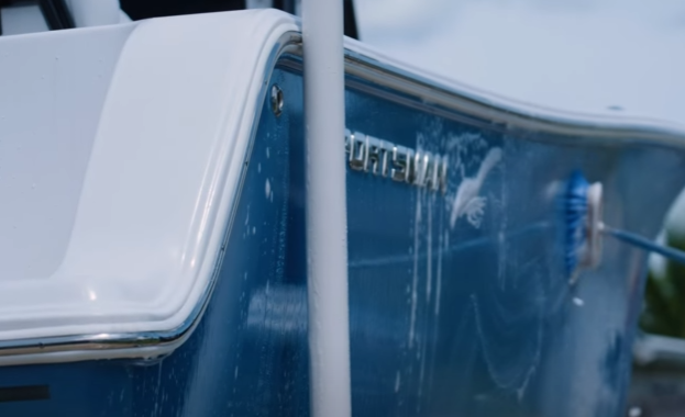 Blue boat on a dock lift getting hosed down with water.