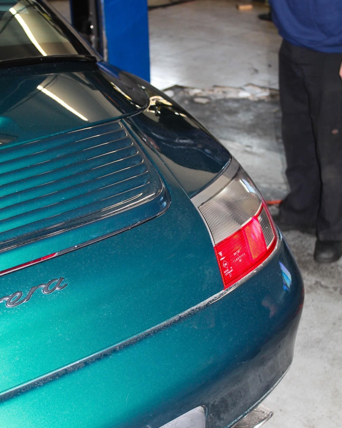 Teal Porsche 911 rear quarter panel with taillight, in a garage.