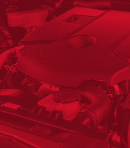 Red-tinted close-up of a car engine, highlighting various components and shapes.