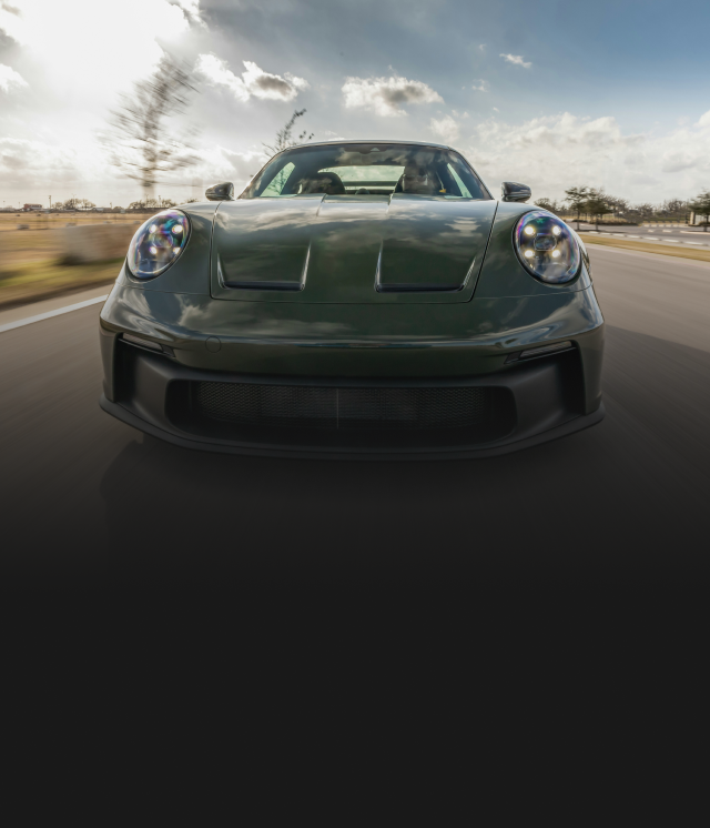 Group of mechanics and a woman posing by a car with an open hood, all wearing blue work shirts.