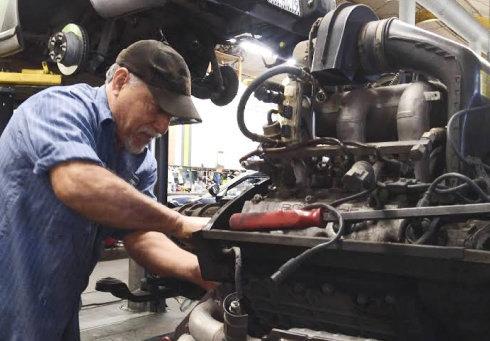 Laptop displaying engine diagnostics data, connected to a blue car's engine.