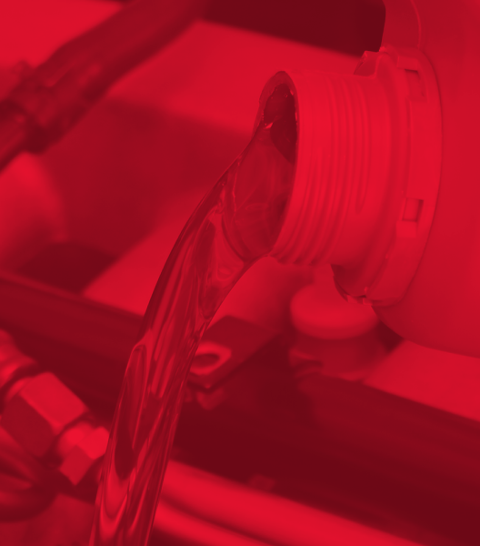 Red-tinted close-up of liquid pouring from a container, possibly into machinery or a tank.