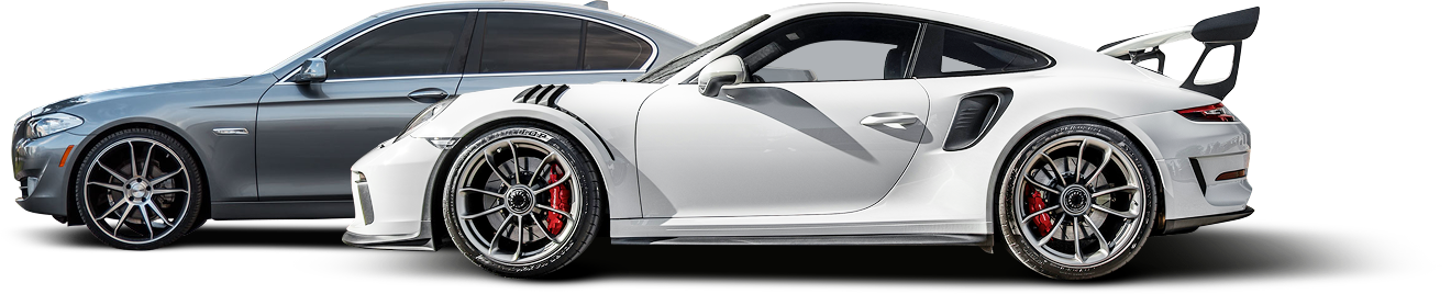 Two cars, a gray sedan and a white sports car with a large rear wing, side by side on a white surface.