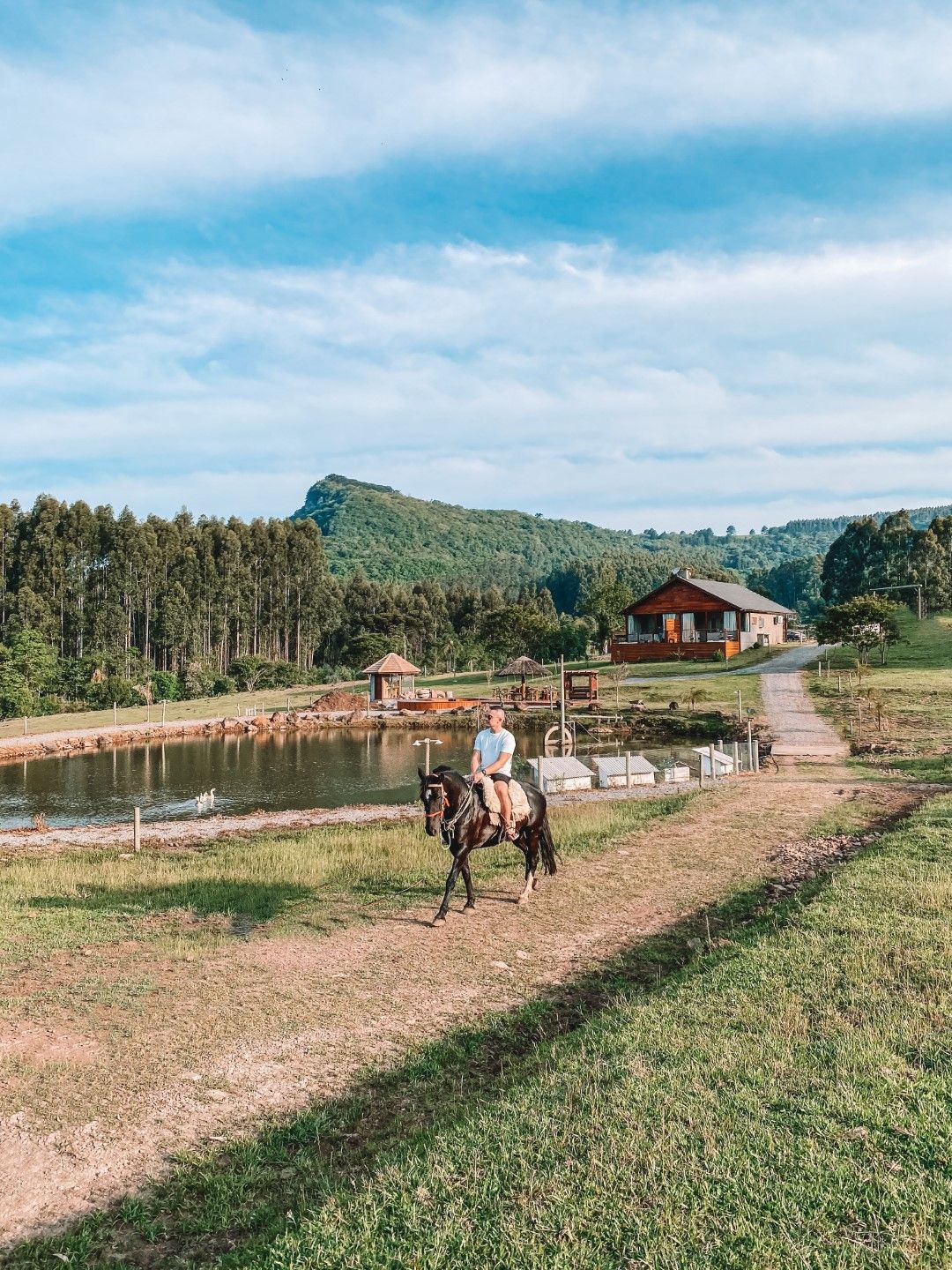 Um homem está cavalgando em um campo próximo a um lago.