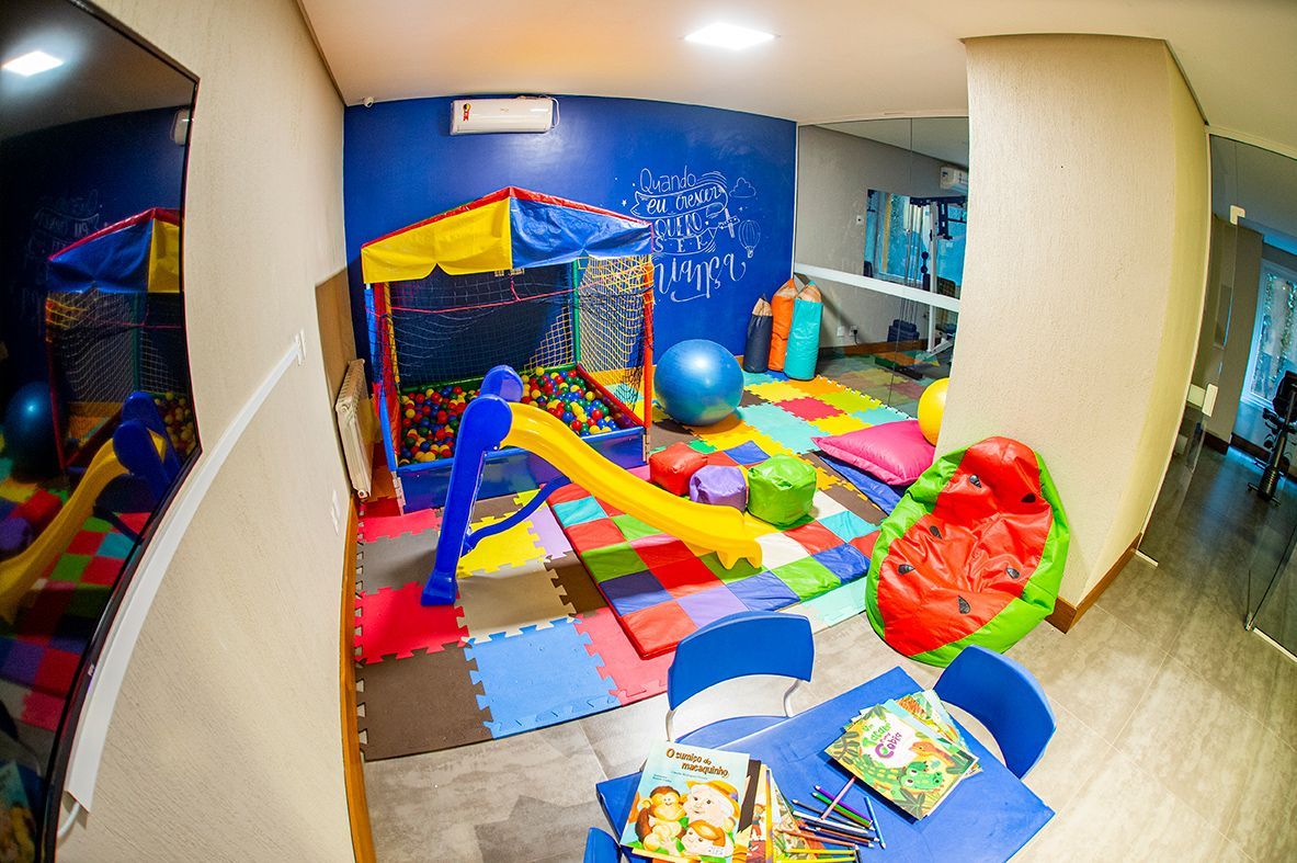 Há um playground no canto da sala com mesas e cadeiras.