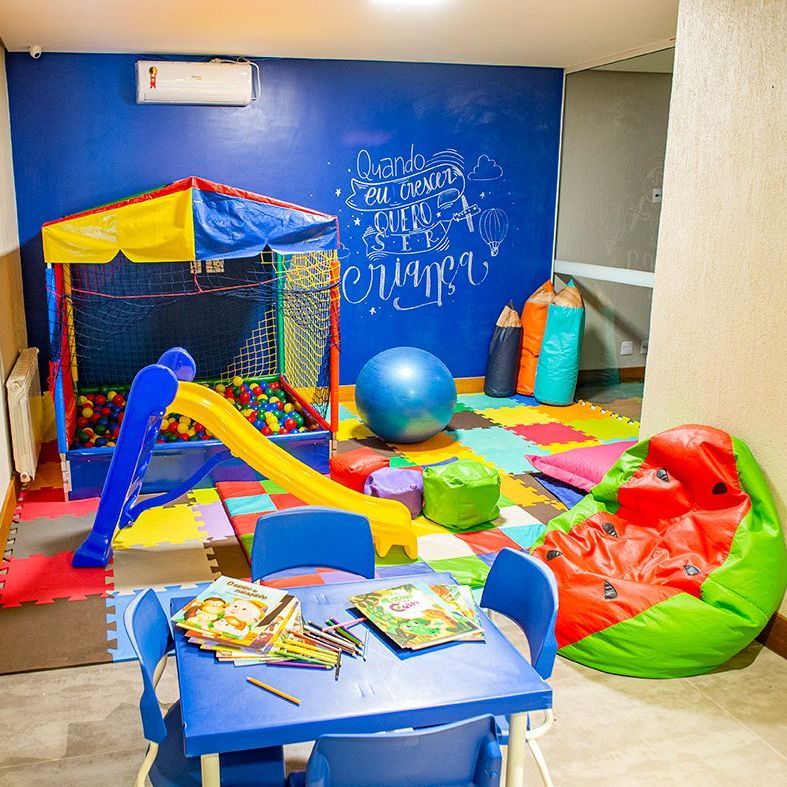 Um quarto infantil com mesa, cadeiras e um escorregador.