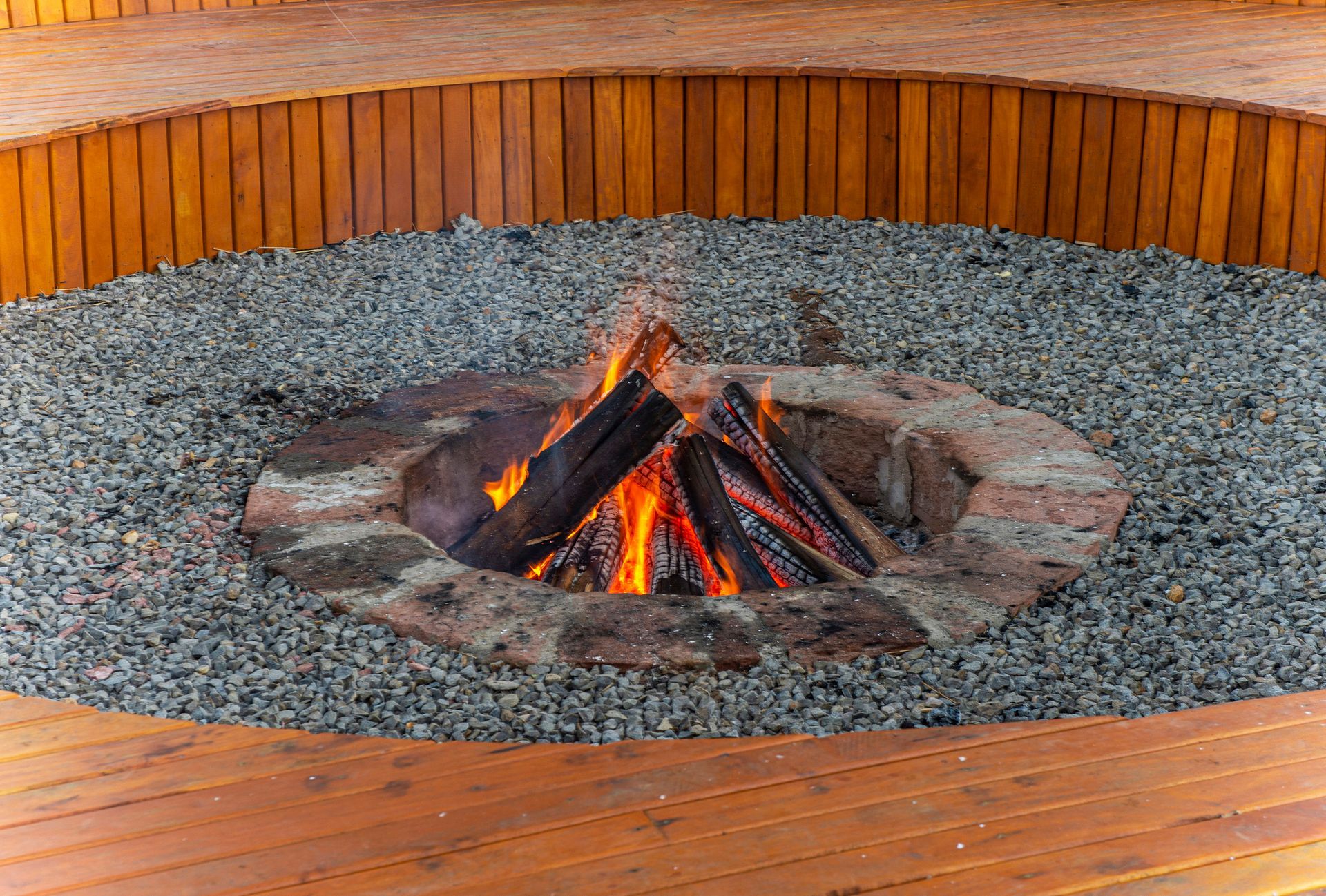 Uma fogueira cercada por cascalho e uma cerca de madeira.