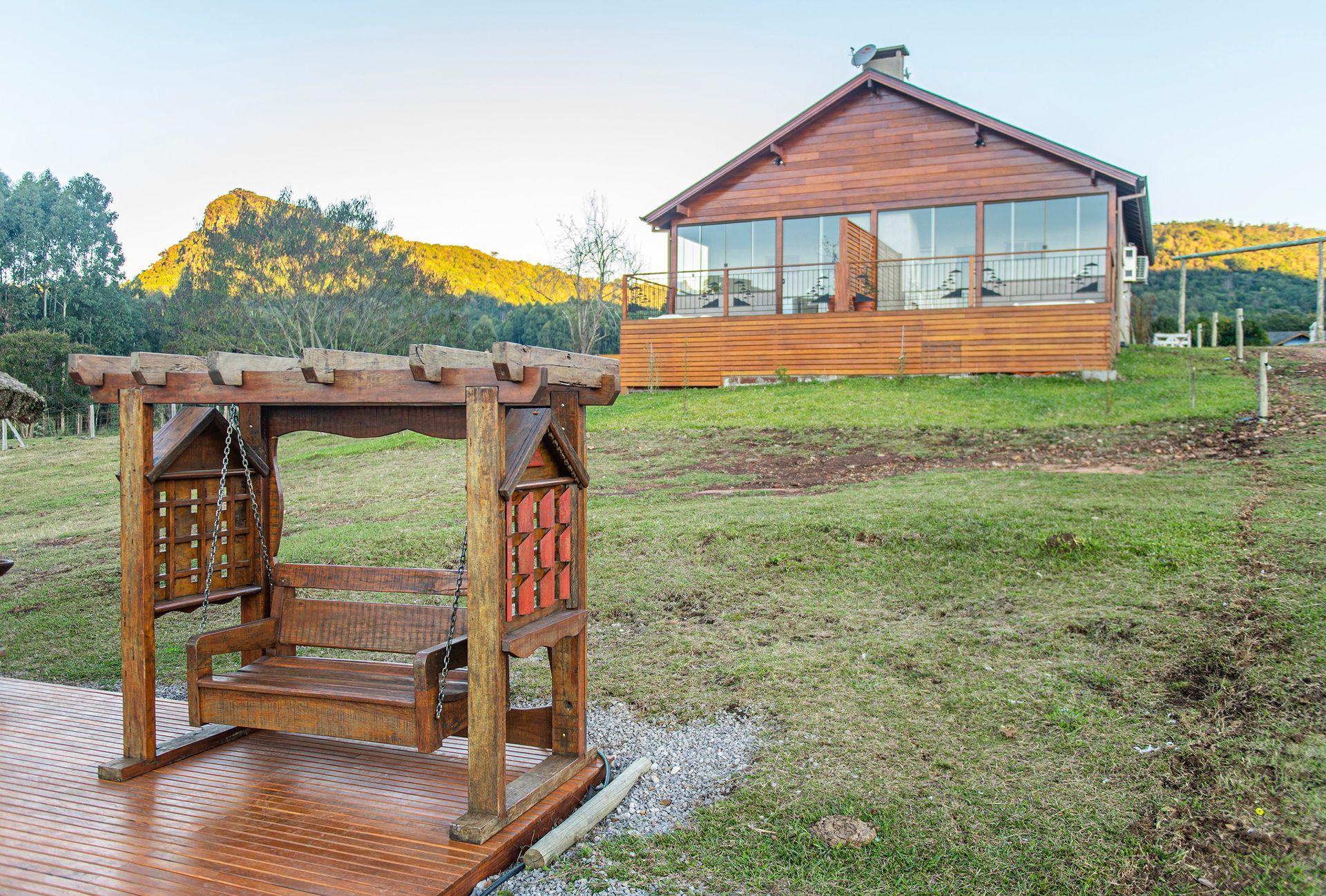 Um balanço de madeira está em frente a uma casa de madeira.