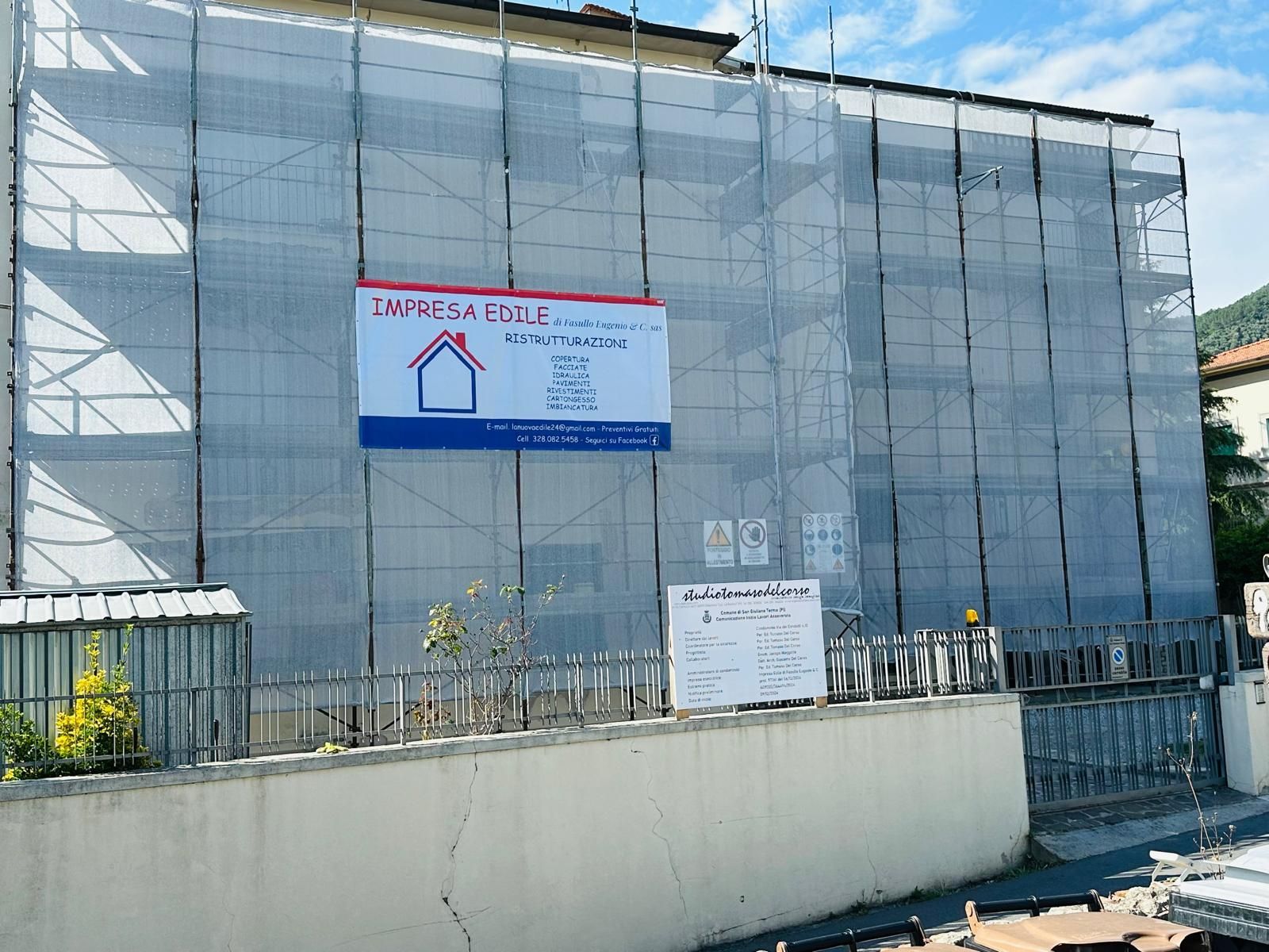 Edificio bianco con portale ad arco e porta in legno scuro; vetrina sulla sinistra, porta del garage sulla destra.