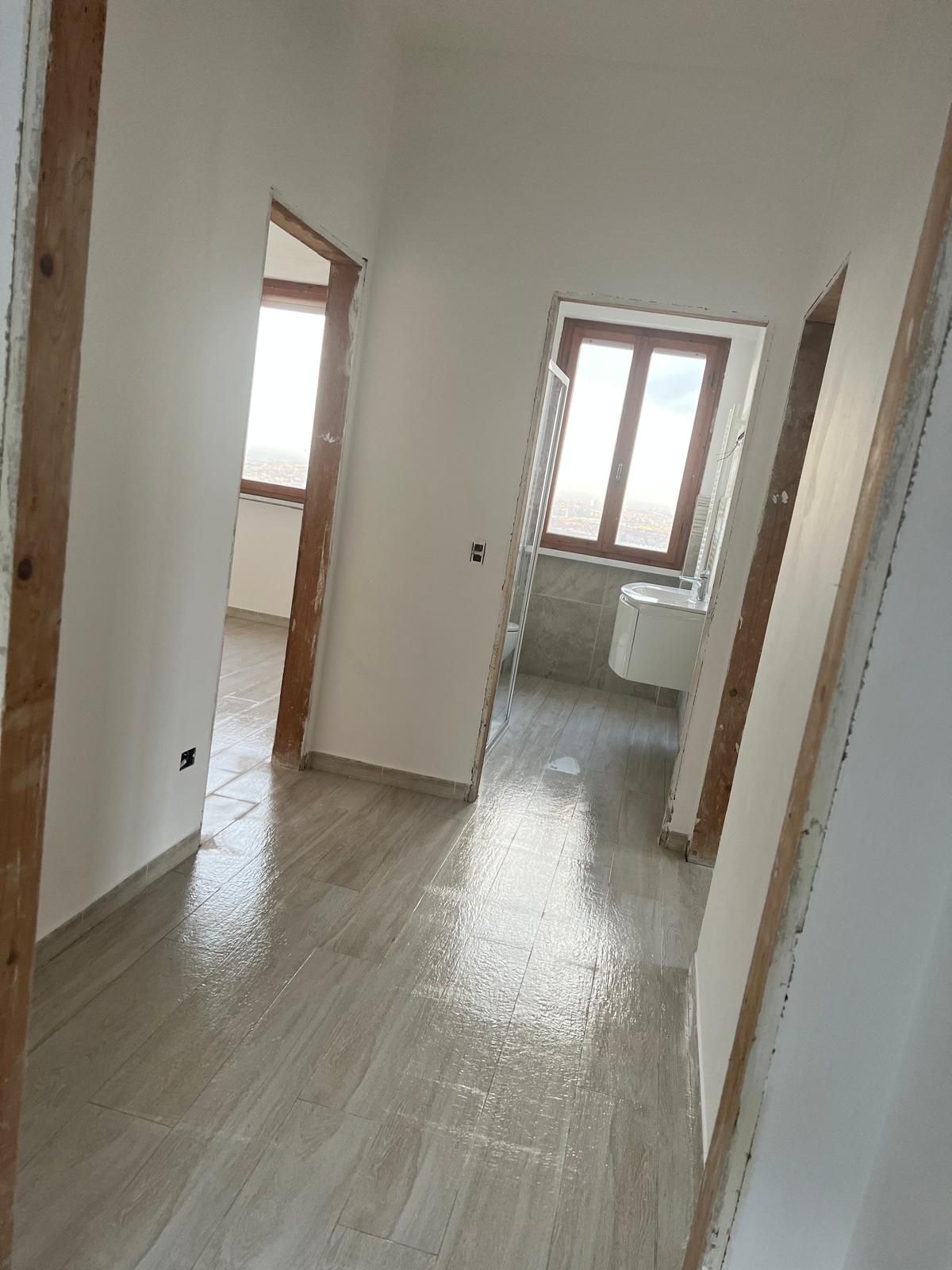 Interno di un ufficio con pareti divisorie in vetro e legno; persona in piedi in un cubicolo.