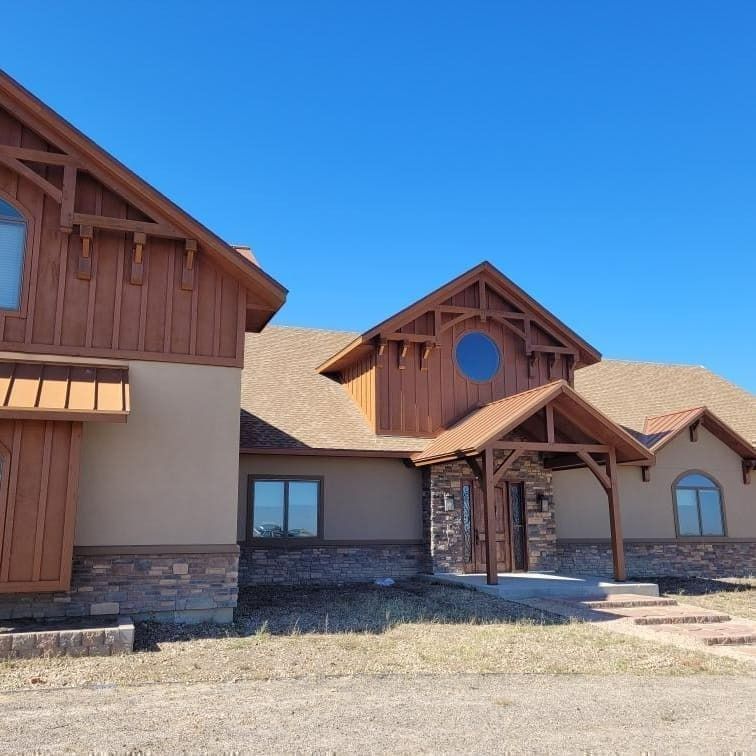 Large brown and tan house with wooden accents and blue sky.