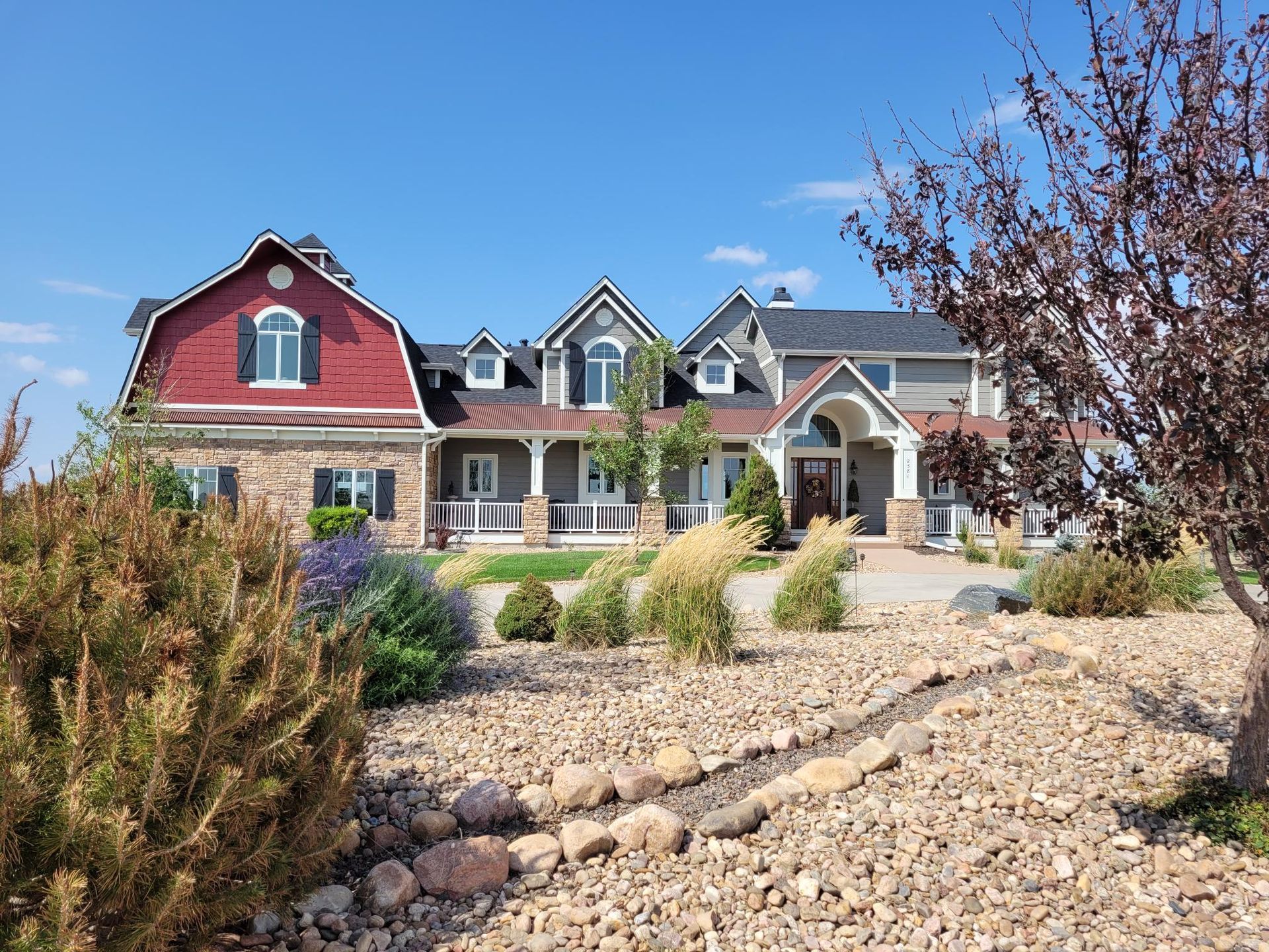 Two-story house with brick base and wood siding. Ladder leans against the brick porch.
