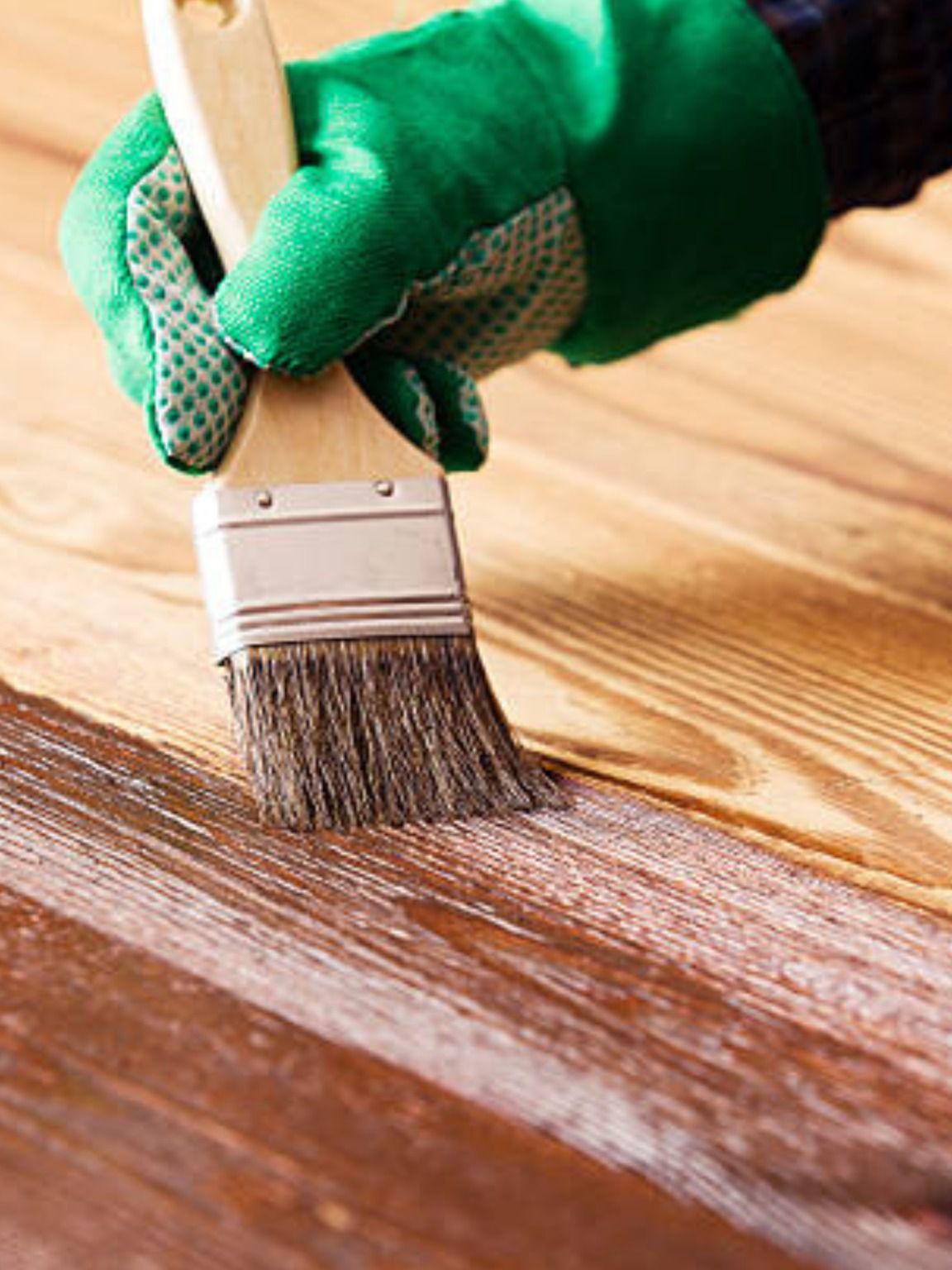 Person applying stain to a wooden bench with a paintbrush.