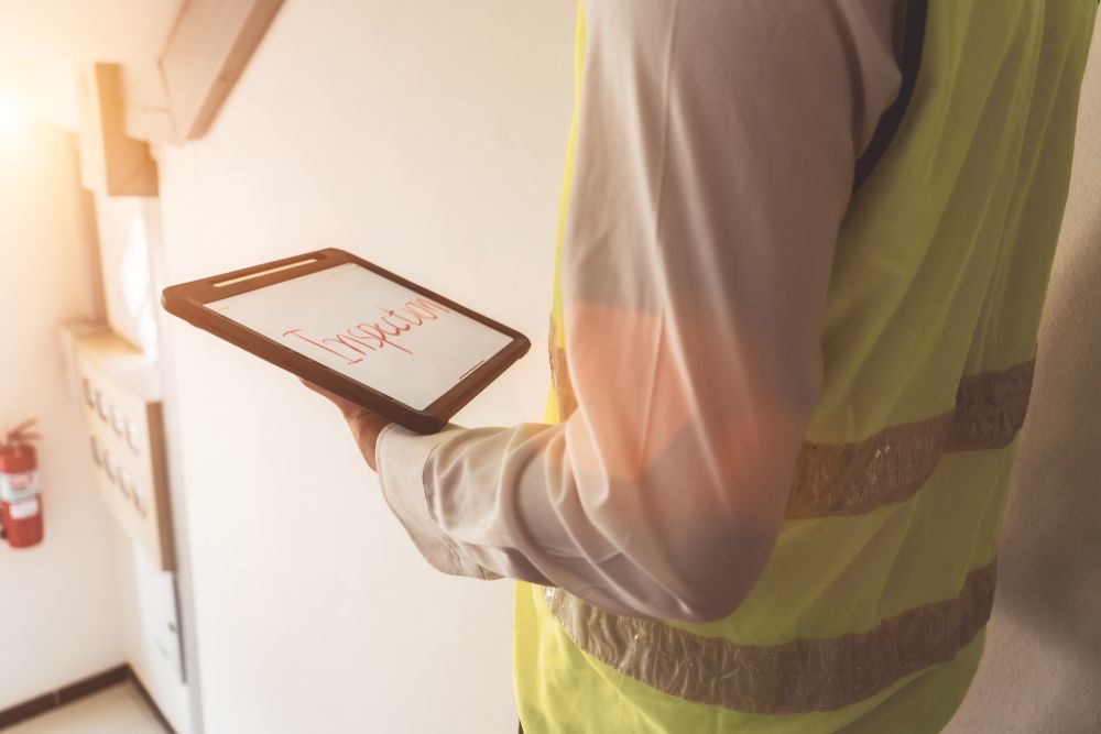 Person in Yellow Safety Vest Holding a Tablet — Scott MacTaggart Building & Pest Inspections In Old Bar, NSW