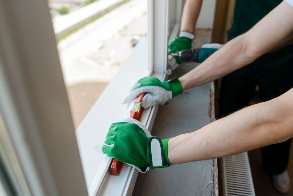 Two People Installing a Window, Using a Drill and a Level — Scott MacTaggart Building & Pest Inspections In Old Bar, NSW