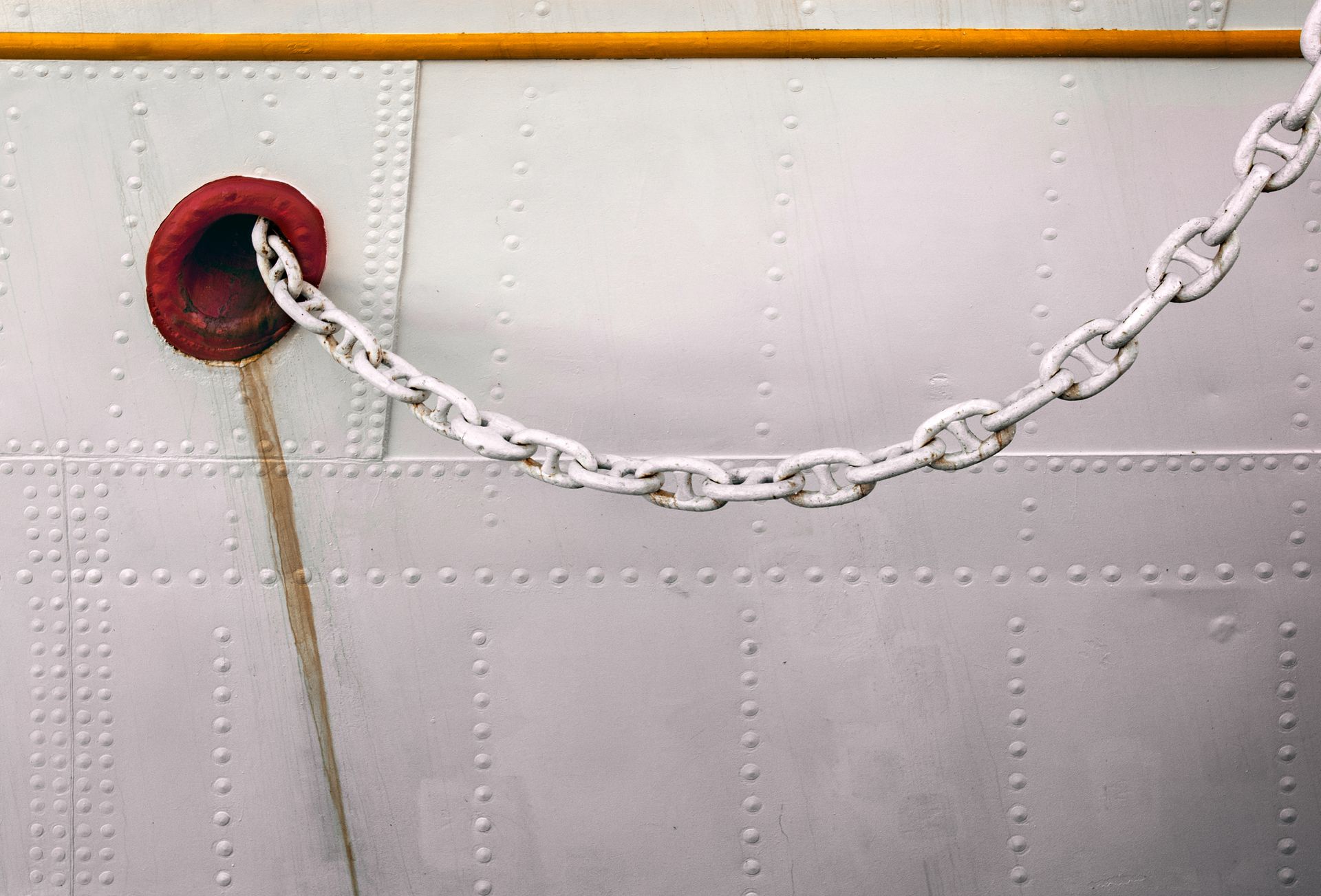 A partial view of a white vessel side with chains.