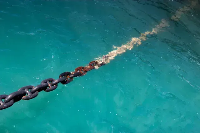 Heavy Anchor chain partially submerged in turquoise water