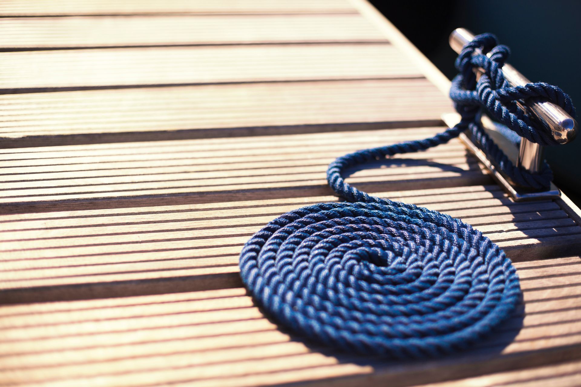 A blue rope is tied to a metal pole on a wooden dock.
