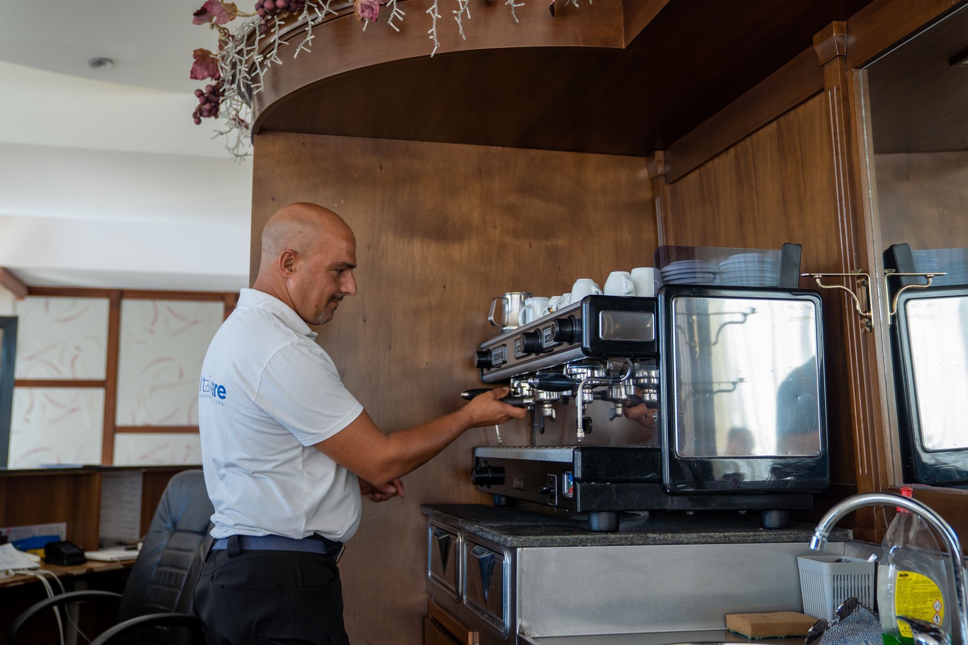 Uomo che aziona una macchina per l'espresso dietro un bancone.
