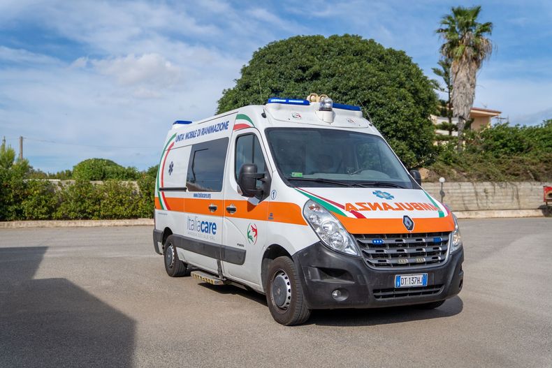 Ambulanza con le porte aperte, personale medico che assiste un paziente su una barella.