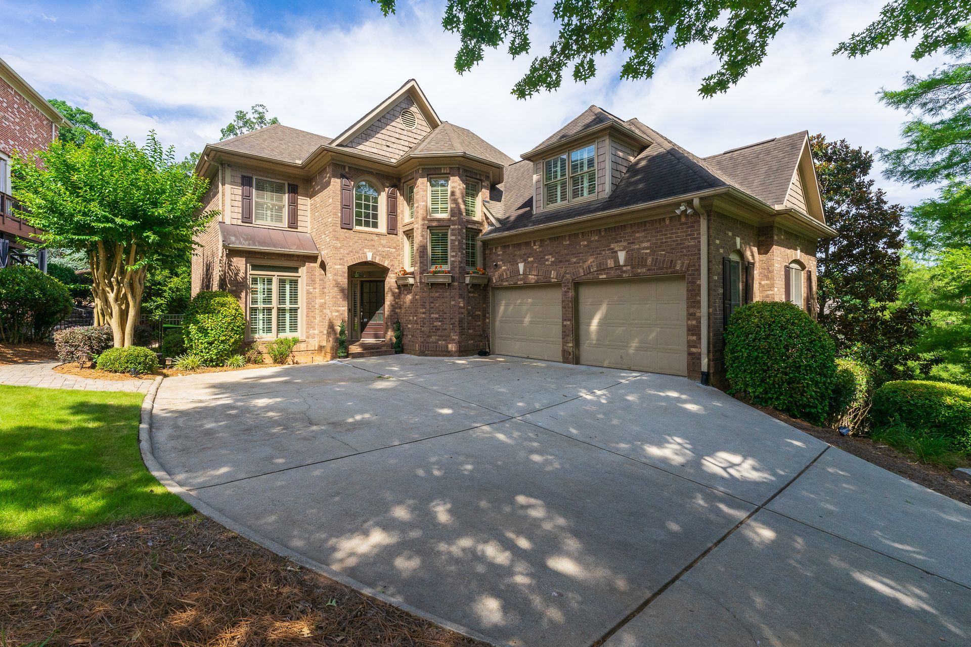 A large brick house with two garages and a concrete driveway.