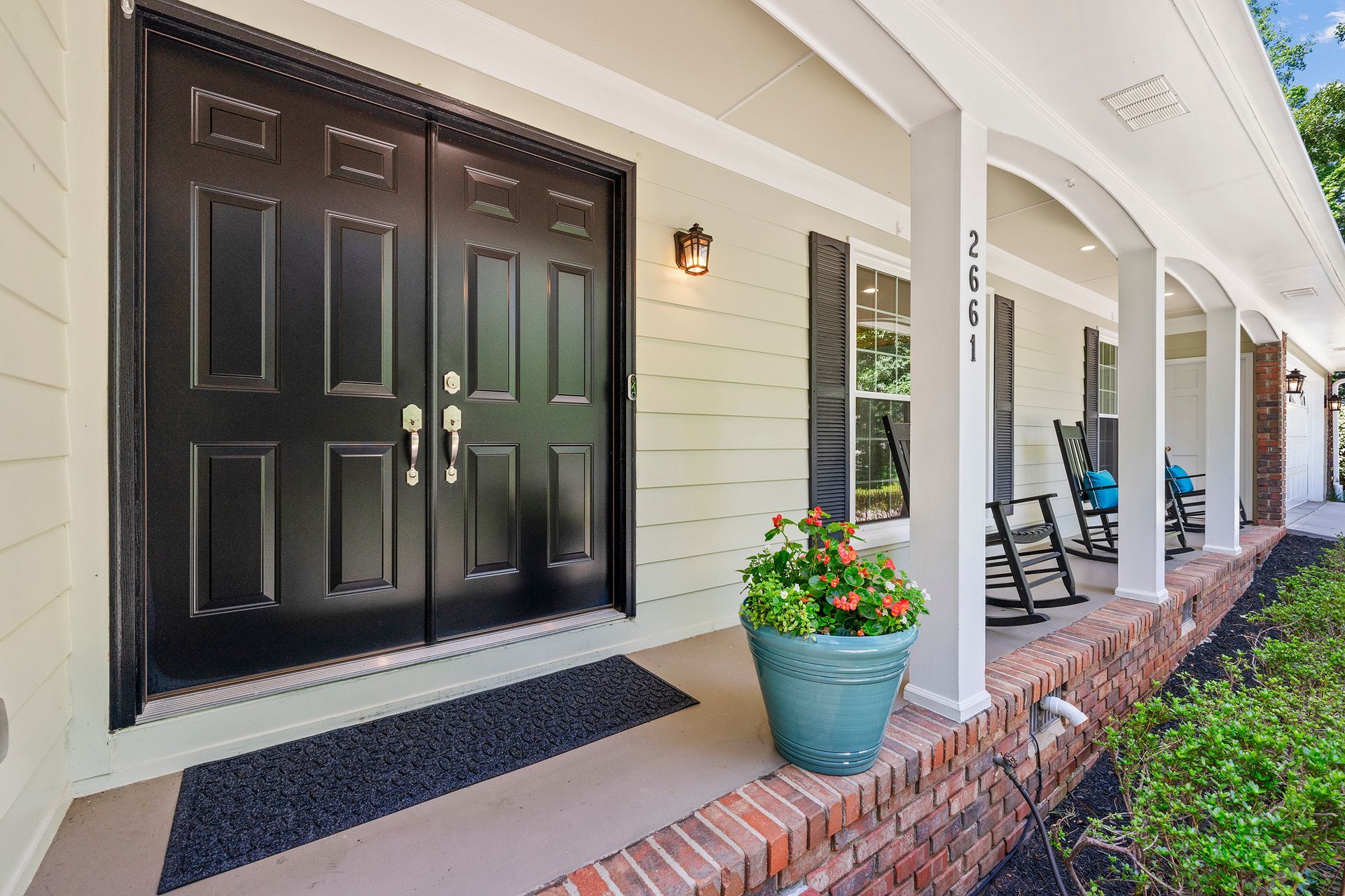 A porch with rocking chairs and a pot of flowers.