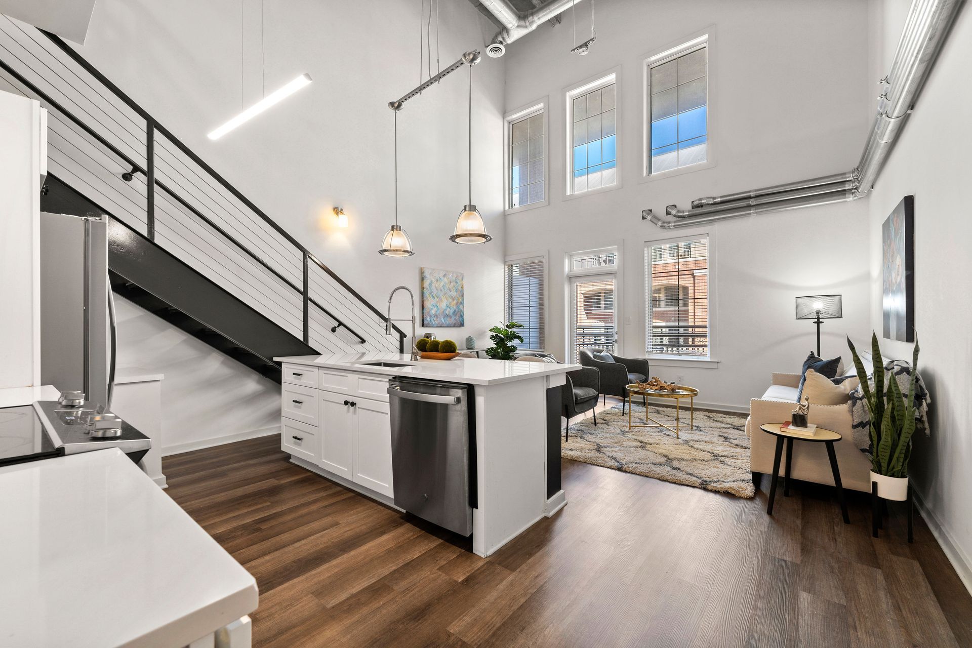 A kitchen , living room , and staircase in a loft apartment.
