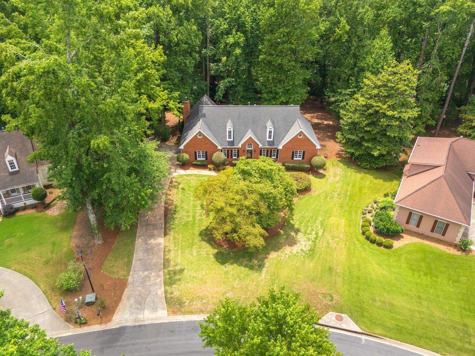 An aerial view of a house in a residential neighborhood surrounded by trees.