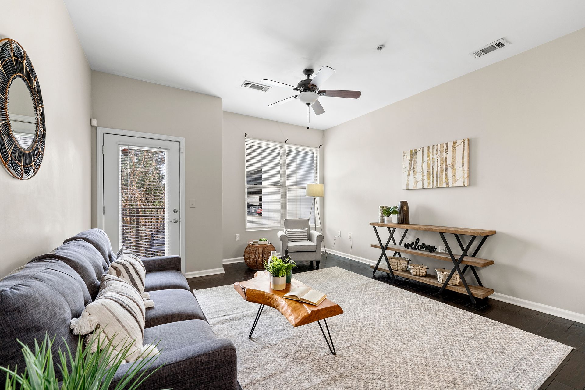 A living room with a couch , coffee table , chair and ceiling fan.