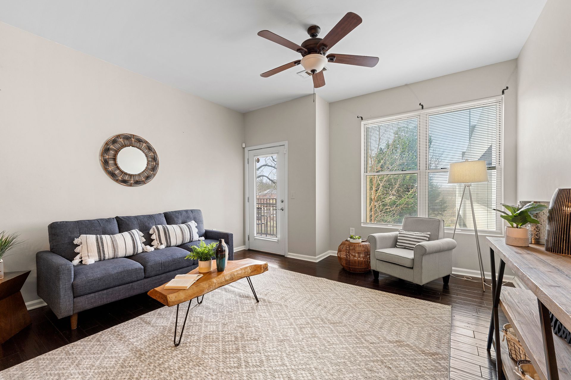 A living room with a couch , chair , coffee table and ceiling fan.