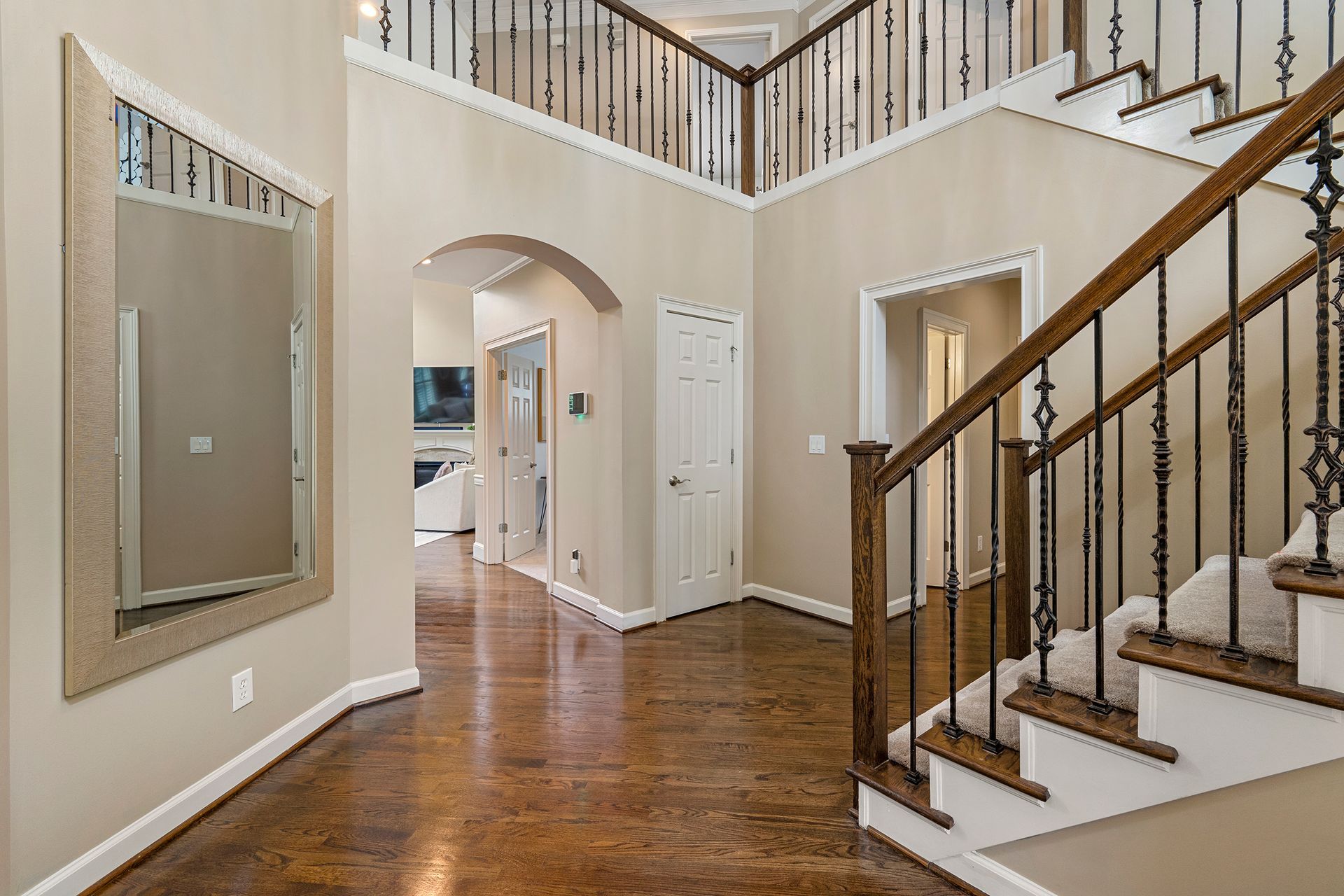 A hallway with stairs and a mirror in a house.