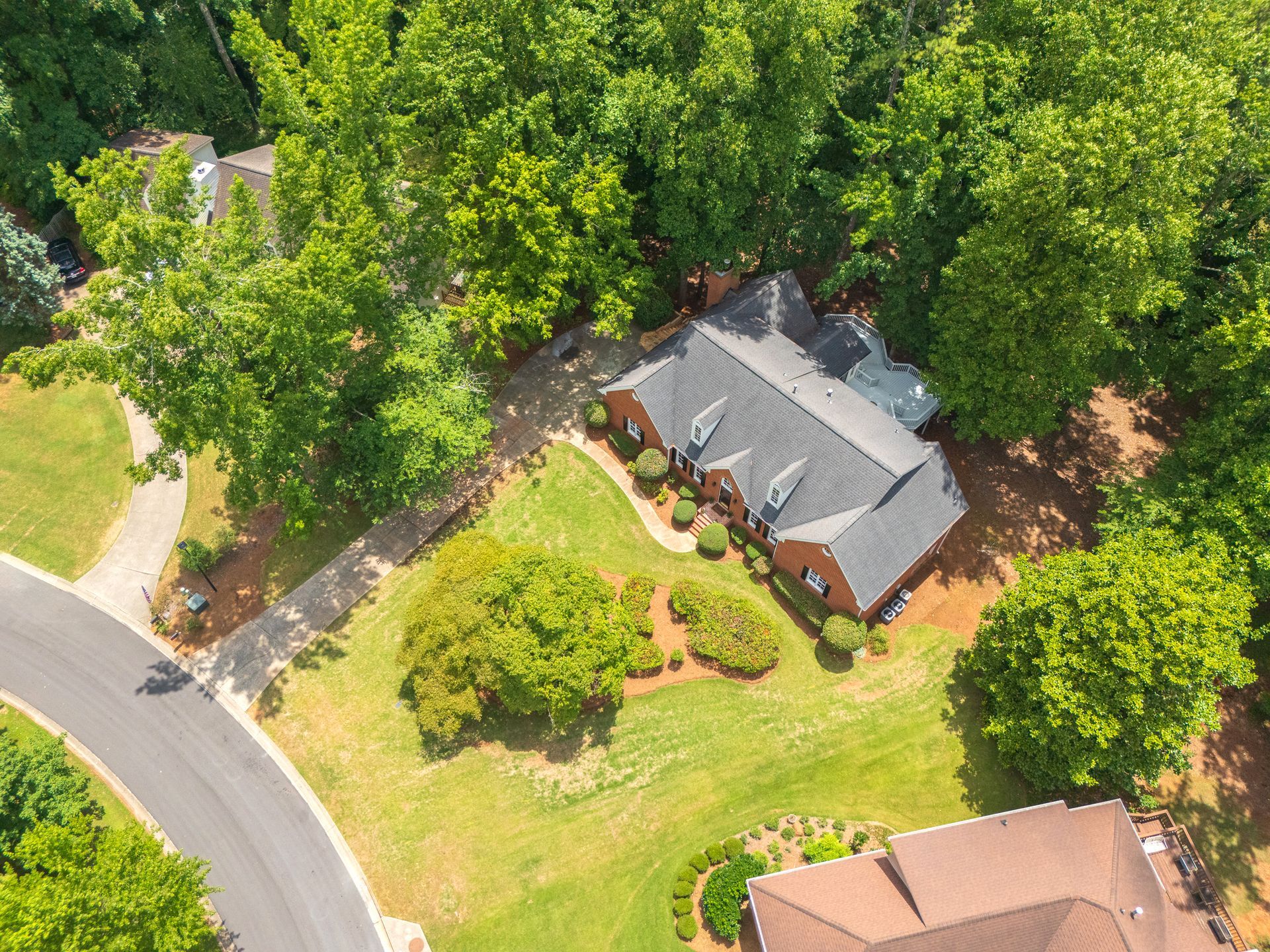 An aerial view of a house in a residential area surrounded by trees.