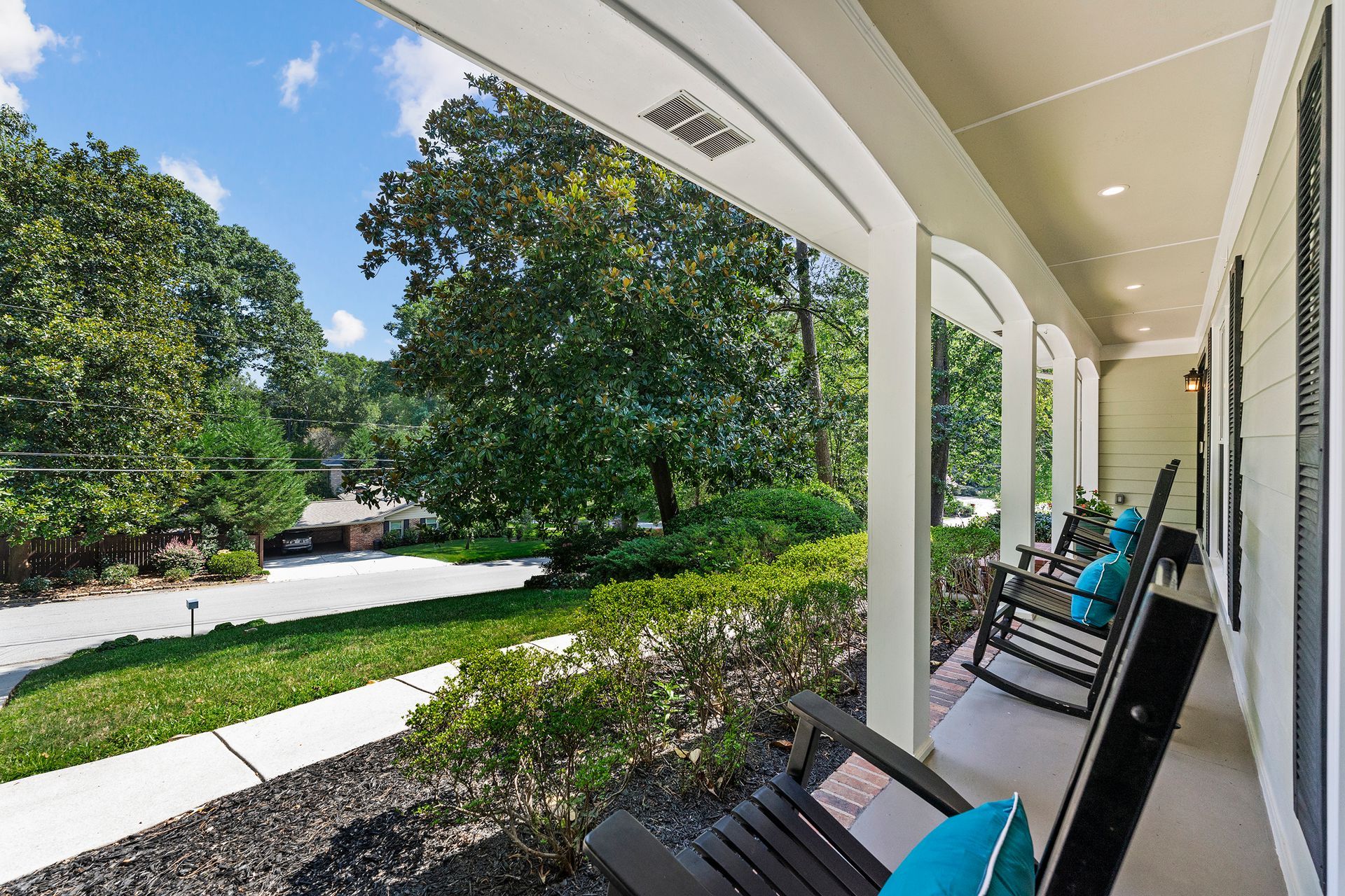 There are rocking chairs on the porch of a house.