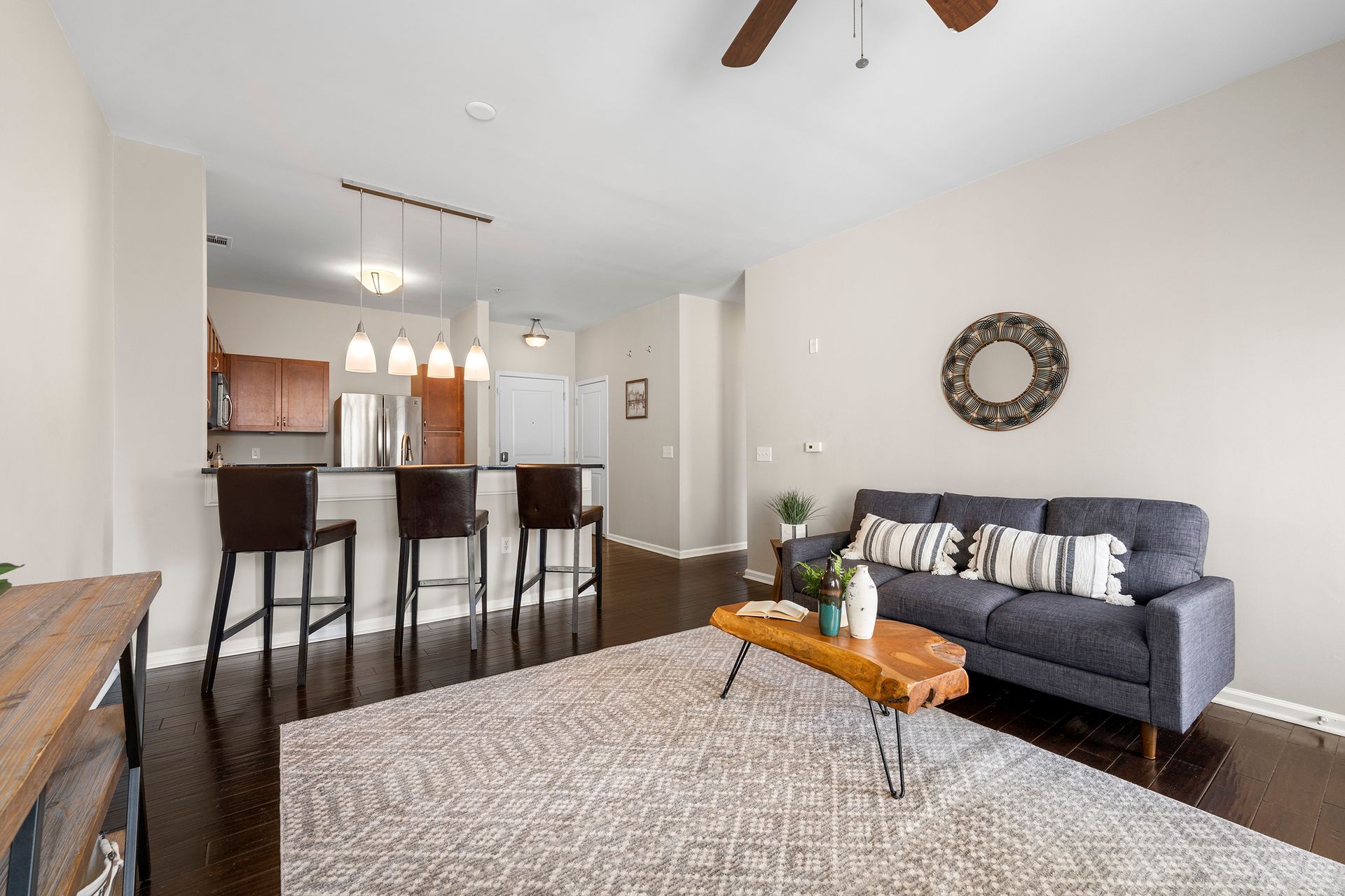 A living room with a couch , coffee table , stools and a ceiling fan.