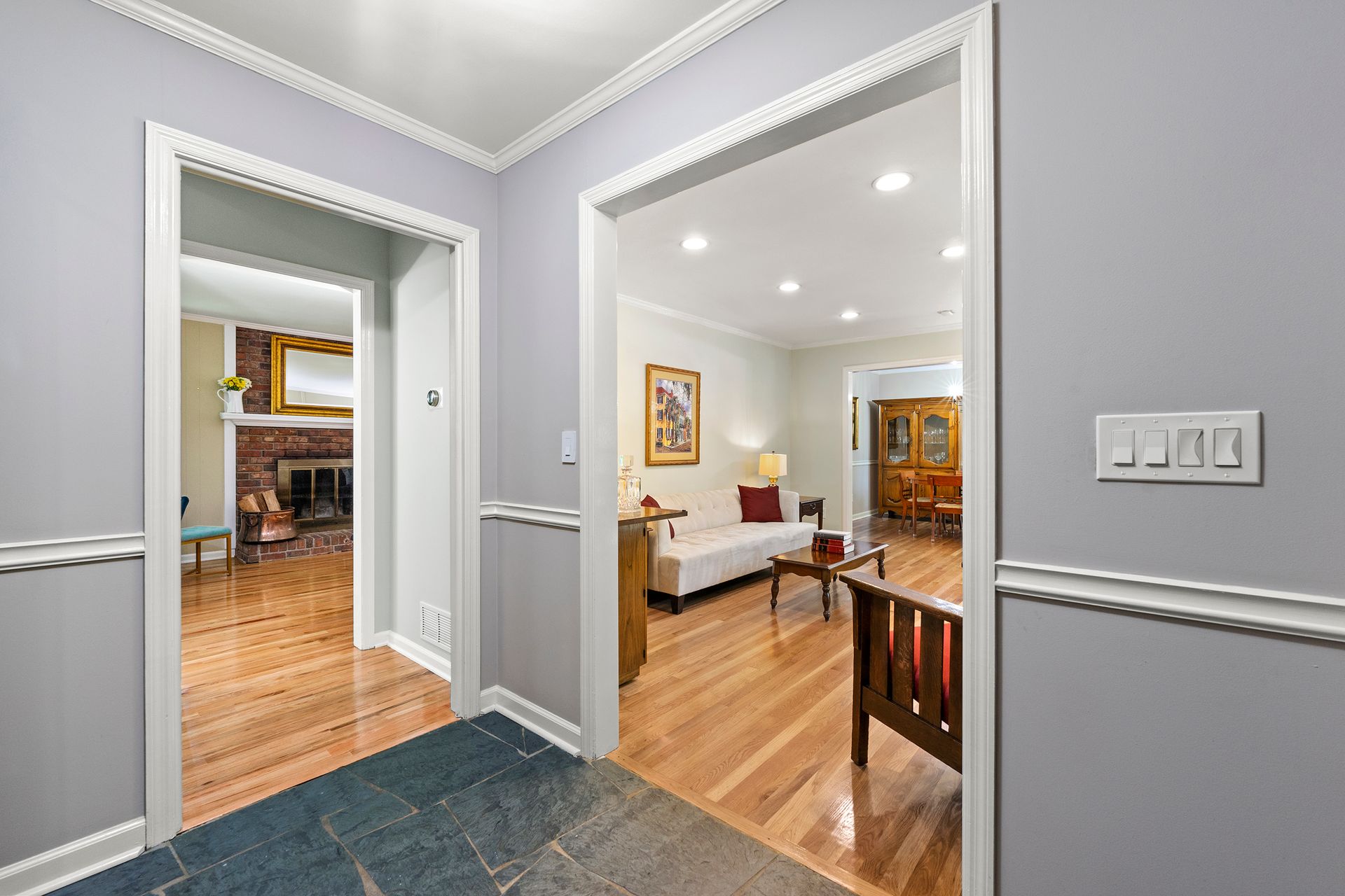 A hallway leading to a living room with hardwood floors and a couch.