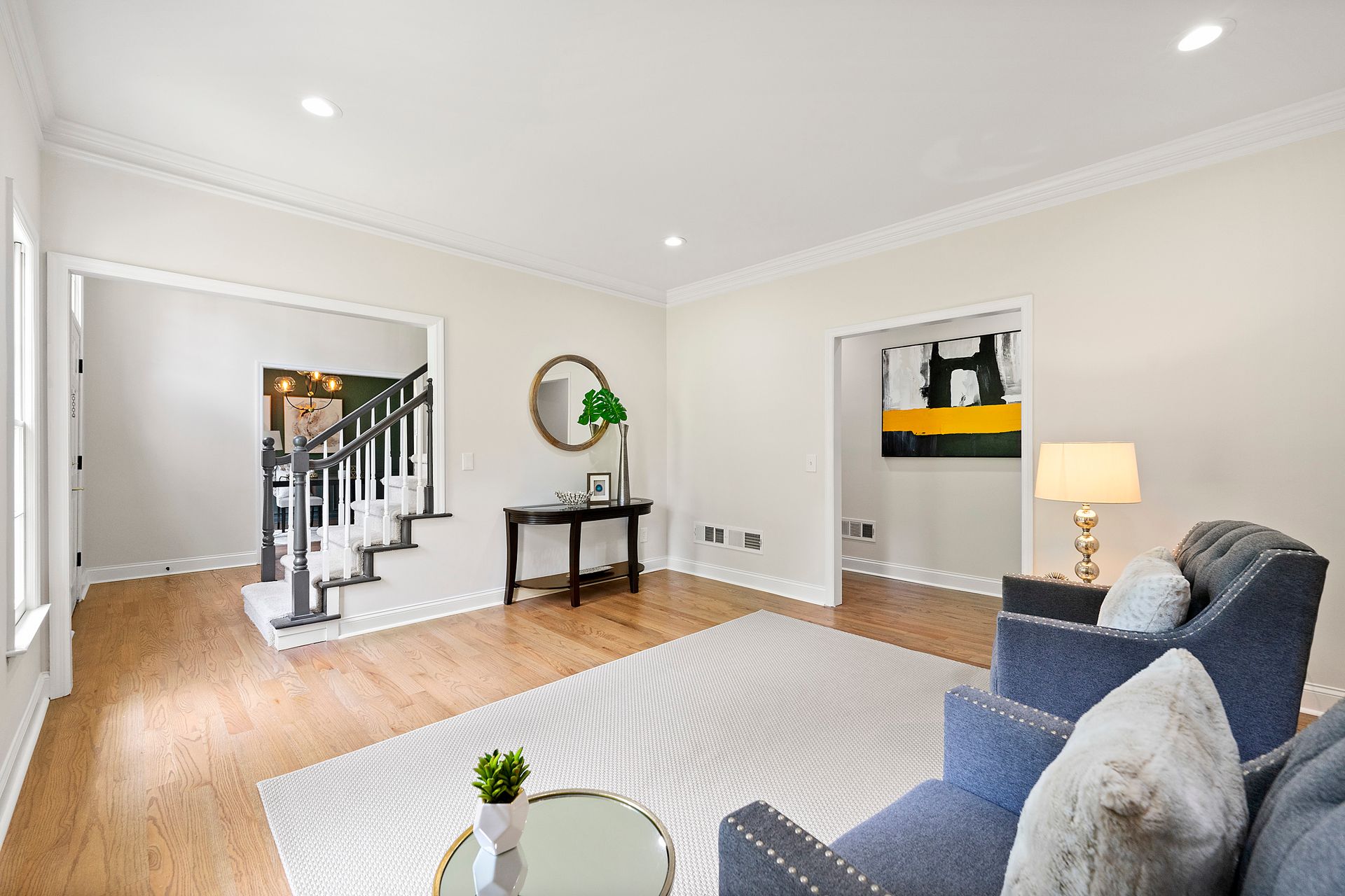A living room with a couch , chair , table and stairs.