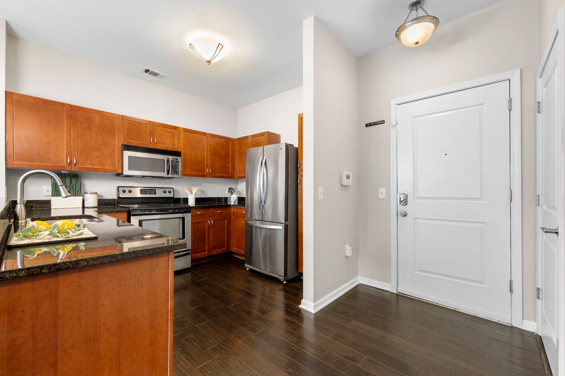 A kitchen with wooden cabinets , stainless steel appliances , a refrigerator and a sink.